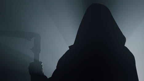 Silhouette-of-grim-reaper-indoors.-Scytheman-standing-in-darkness.