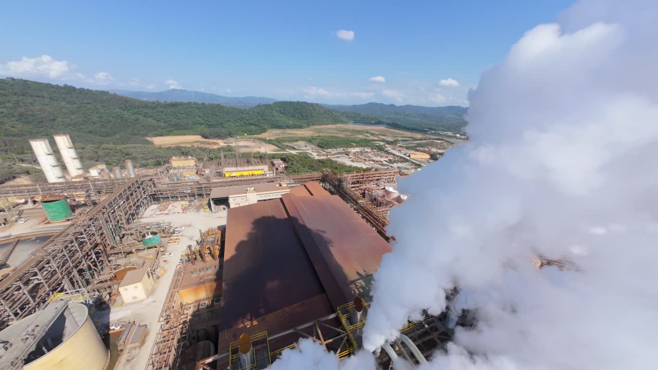 Industrial processing plant of open-pit gold and silver mine at Cotui, steam, machinery, mining, heavy industry, environmental themes, Dominican Republic. Aerial drone FPV