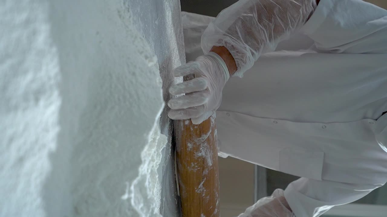 chef de pastelería turco enrollando la masa usando un rodillo, video en cámara lenta, video vertical
