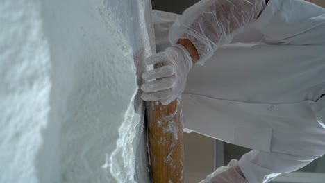 turkish pastry chef rolling out dough using a rolling pin, slow motion video, vertical video