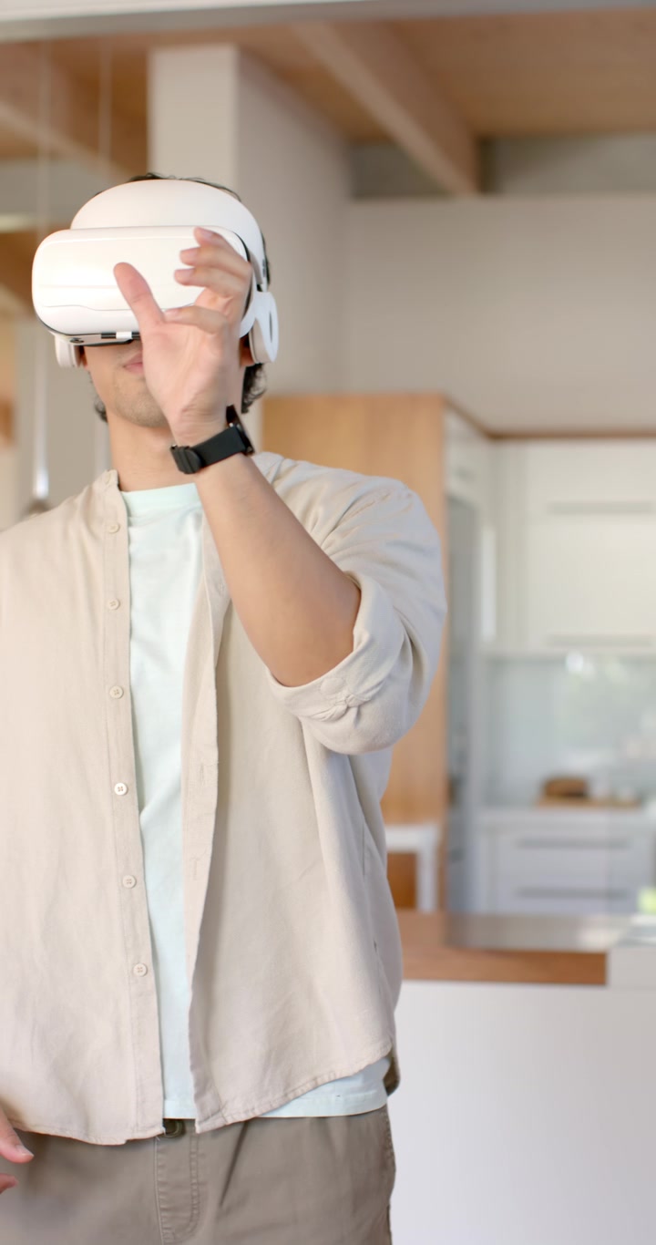 Video verticale: Uomo africano adulto che indossa un visore VR bianco, manipola controlli virtuali in cucina.
