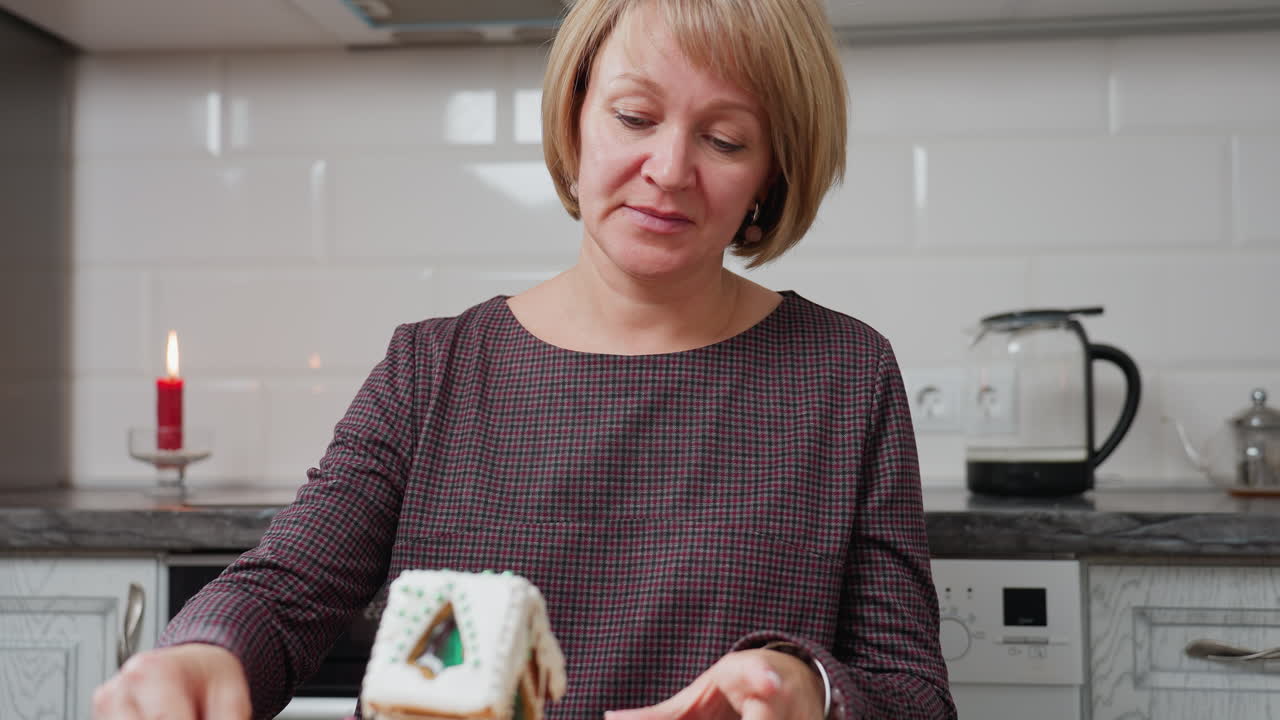 mujer en vestido a cuadros sentada en la cocina, girando cuidadosamente el pastel decorado en una bandeja de madera, luz de vela cálida, backsplash de azulejos blancos, hervidor eléctrico y cocina rústica