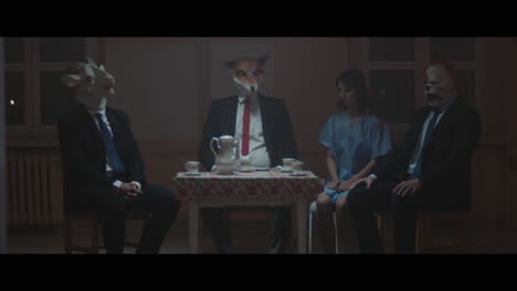 a girl sits at a table with strange figures in animal masks