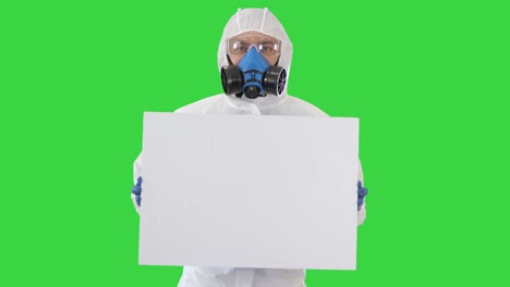 lab scientist in safety suit holding empty white board on a green screen, chroma key