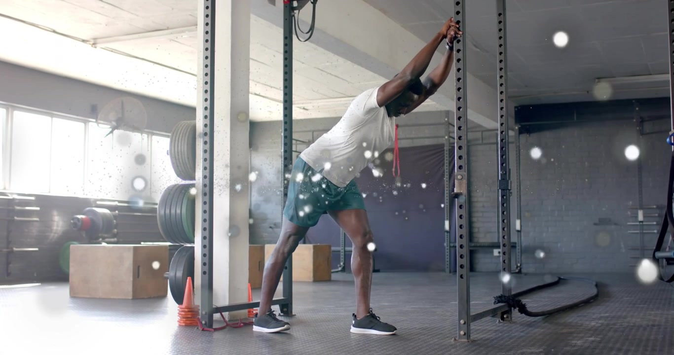 Gym user looping red band on rack holding hamstring stretch for calf release then releasing band