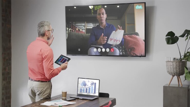 Caucasian businessman on video call with african american male colleague on tv screen