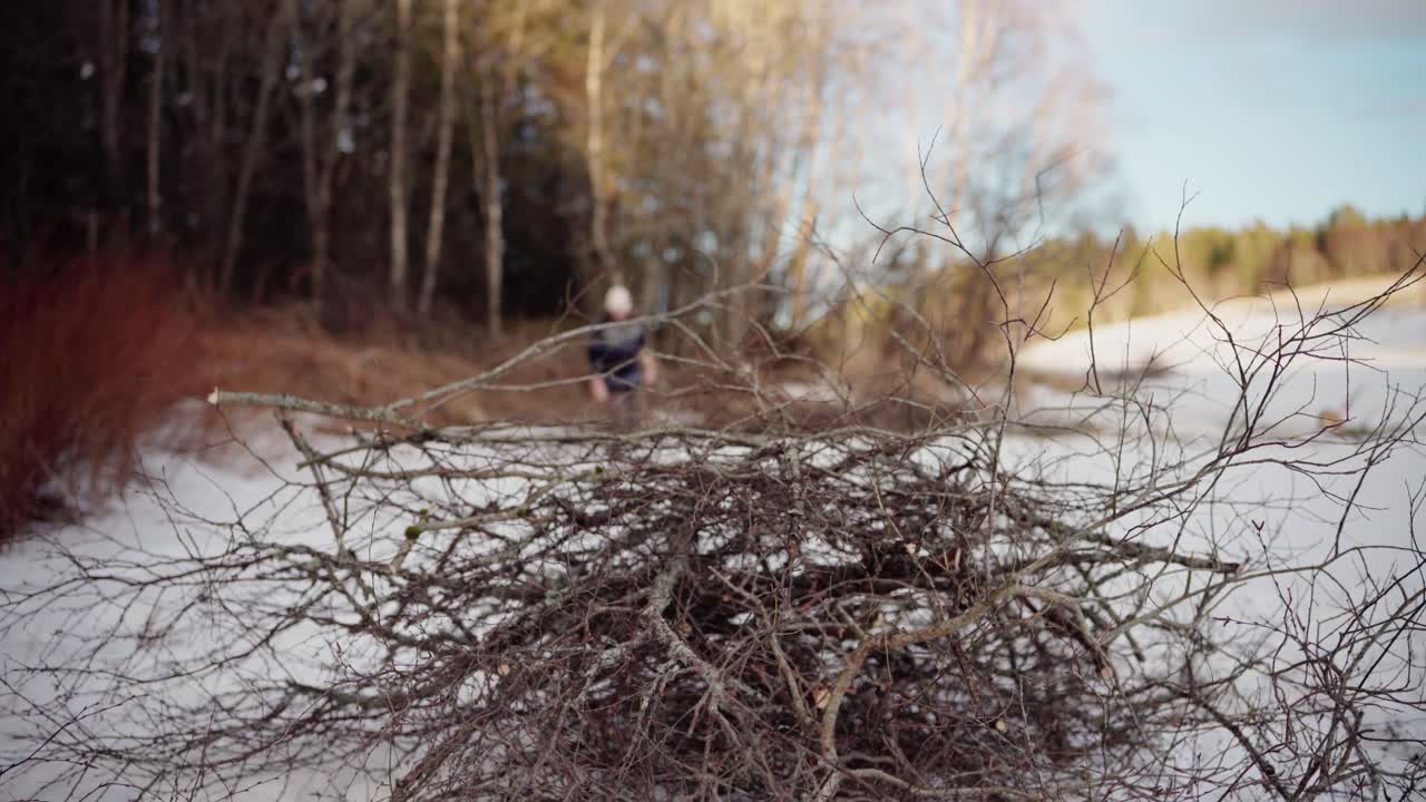 En mand slæber en bunke optændingsbrænde til opvarmning på en vinterdag - Statisk optagelse