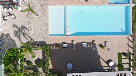 aerial top down shot of terrace with empty swimming pool during sunny day in hotel area