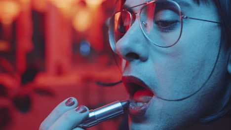 hombre transgénero poniéndose lápiz labial en un bar