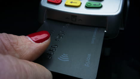 mujer con la mano poniendo la tarjeta de crédito en la terminal pos. mujer usando la terminal de dinero.