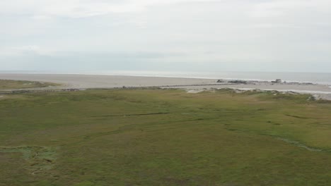 cinematic drone - aerial shot of the green and sandy nature beach of st. peter ording at the north sea, schleswig holstein, germany, 25p