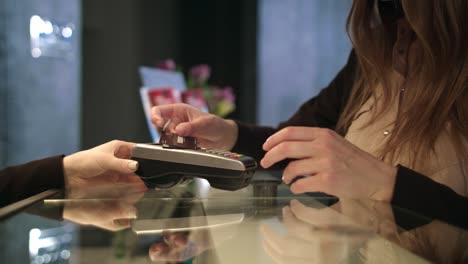 Female-hands-using-plastic-card-at-hotel-reception.-Woman-paying-by-credit-card