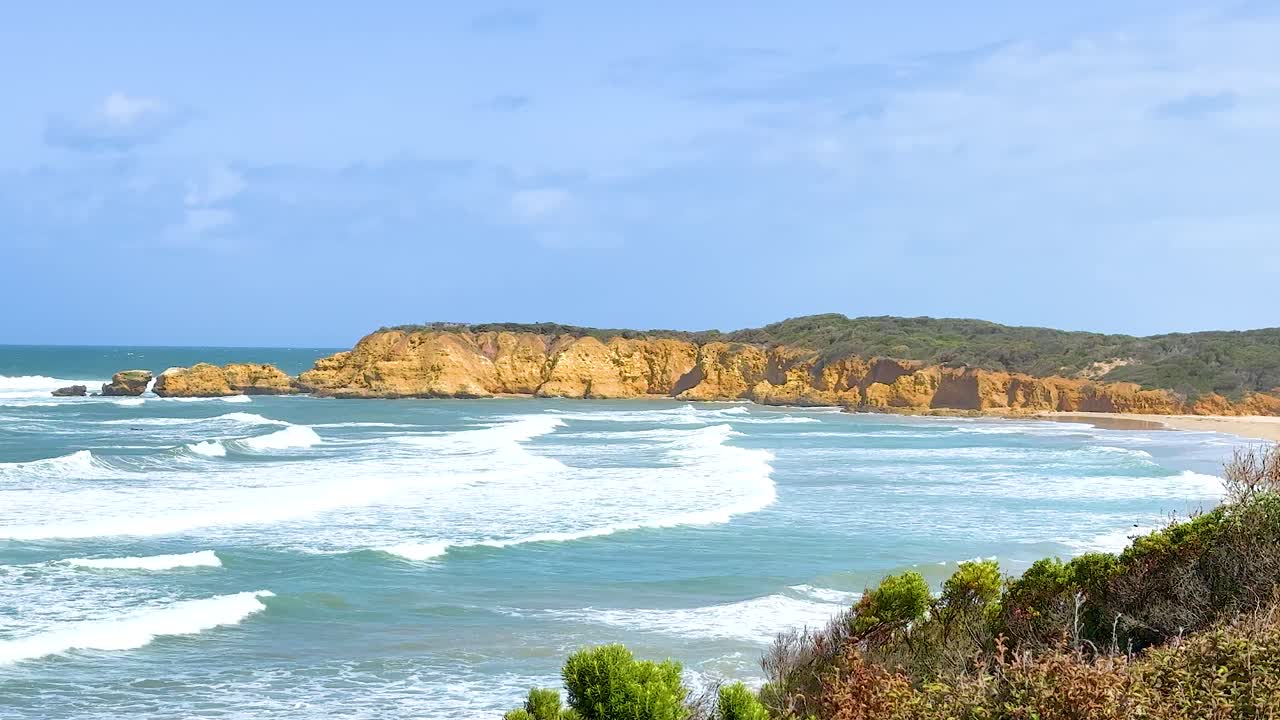Dynamic waves crash against the rocky coastline of Torquay, Victoria, under bright daylight, showcasing natural beauty and movement