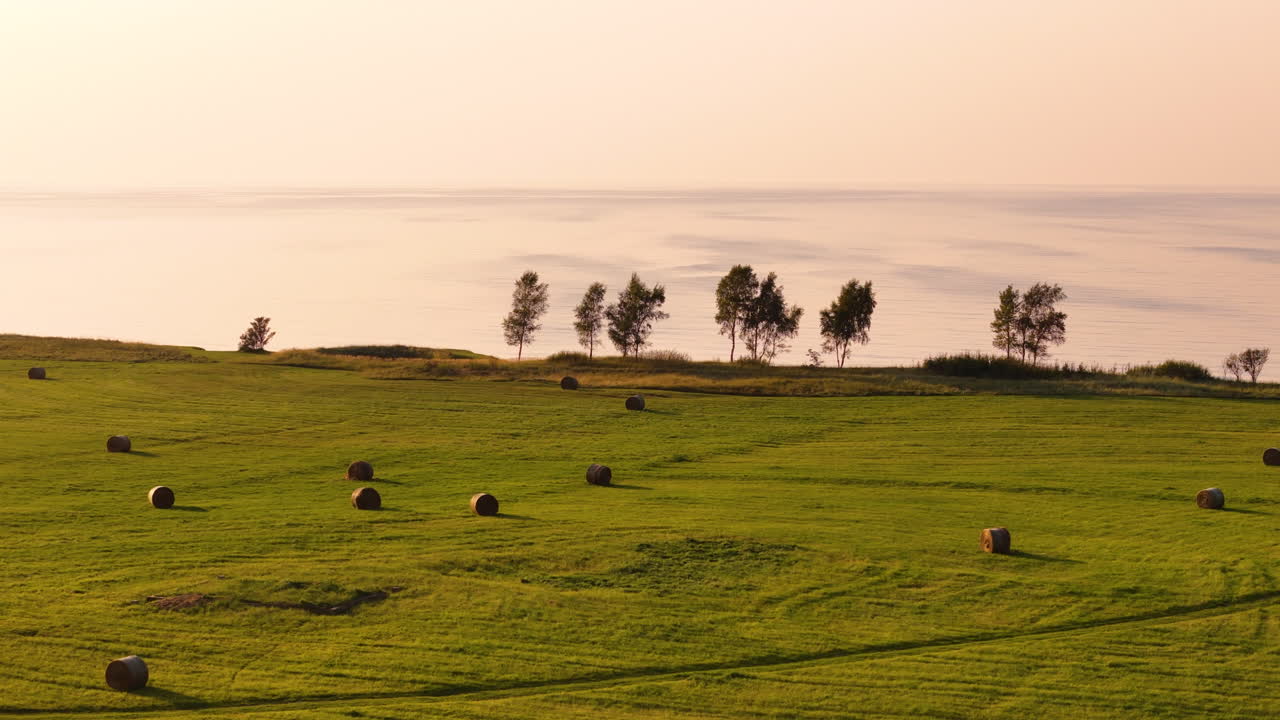 amanecer sobre un campo de heno junto al lago