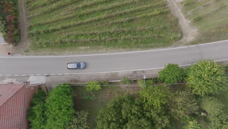 Imágenes-Aéreas-De-Arriba-Hacia-Abajo-Que-Siguen-A-Un-Automóvil-Plateado-Que-Circula-Por-Una-Carretera-En-El-Norte-De-Italia