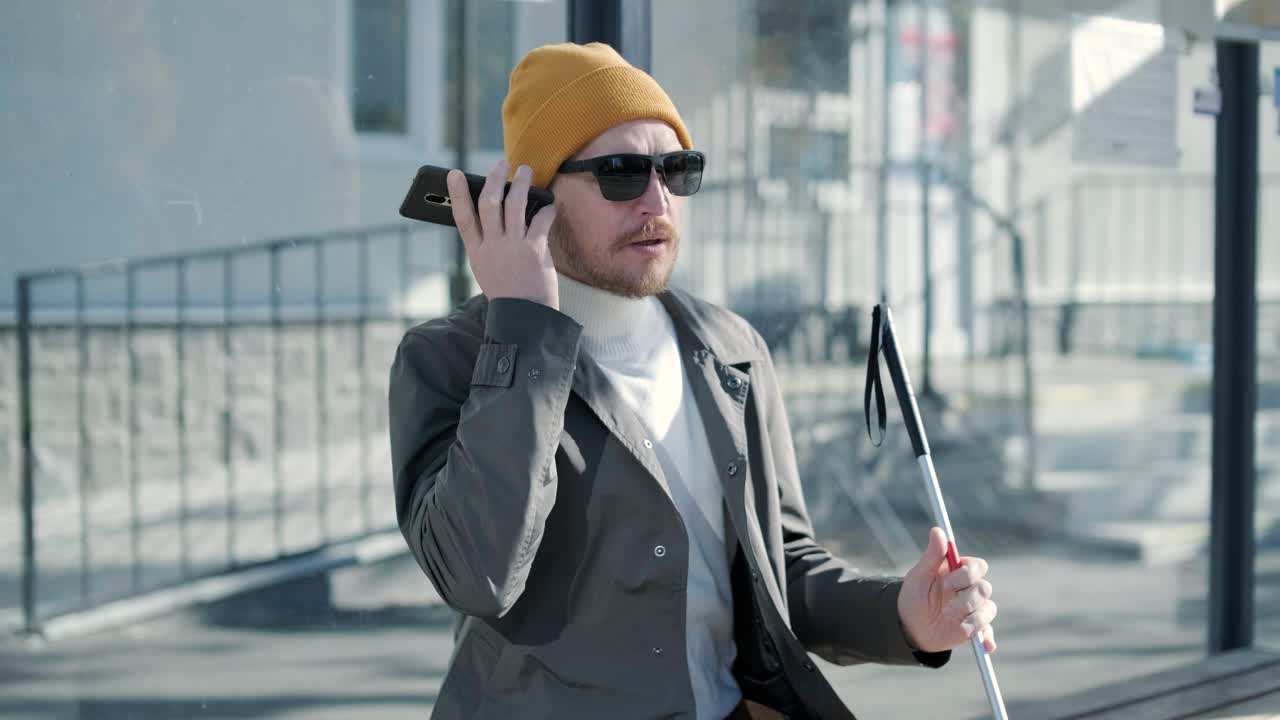 시내의 벤치에 앉아서 전화를 하는 시각장애인.