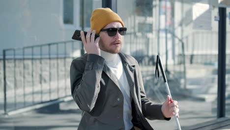 visually impaired man talking on the phone, sitting on the bench in the city.