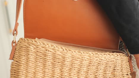 woman's hand placing a phone in a straw bag