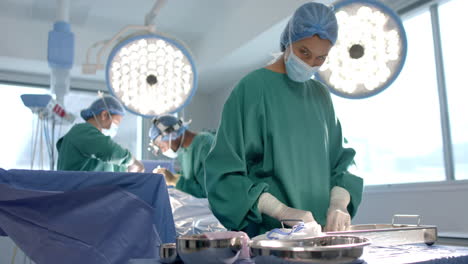 portrait of biracial female surgeon sorting surgical tools in theatre, copy space, slow motion