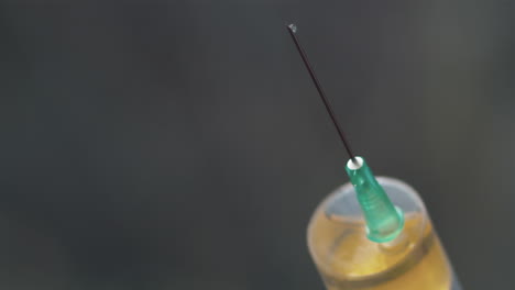 medication drips from syringe needle, extreme close-up