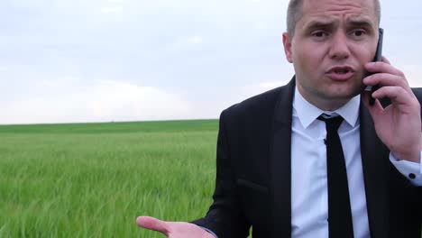 man in suit talking on phone in field