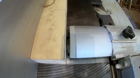 carpintero que trabaja en un taller, artesano que aserró una barra de madera en una máquina de lijar. artesano profesional que prepara barras de madera para la fabricación de muebles. industria de carpintería y carpentería dura