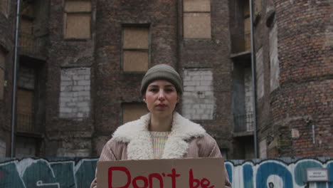 Young-Girl-Looking-At-Camera-And-Raising-A-Cardboard-Placard-With-The-Phase-Dont-Be-Mean-The-Planet-During-A-Climate-Change-Protest