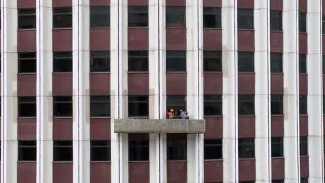 limpiadores de ventanas de pie en una plataforma suspendida limpiando ventanas de rascacielos