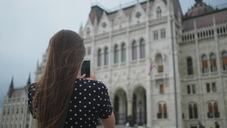 woman taking picture of the hungarian parliament building