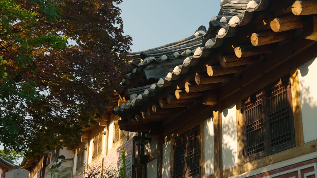 Warm sunset light glows on traditional hanok rooftops and wooden eaves in Bukchon Hanok Village, Jongno-gu, Seoul