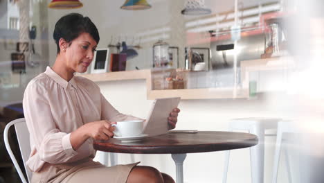 mujer de negocios en una mesa en un café usando una computadora tablet