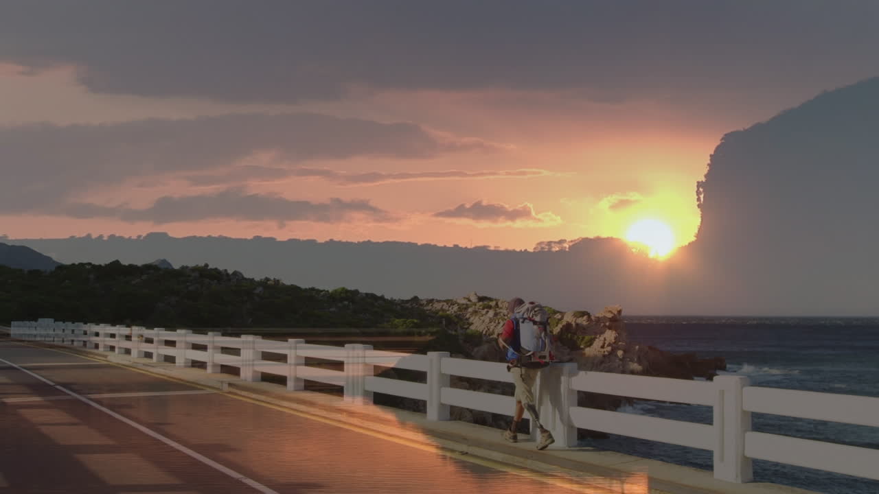 cielo al atardecer contra diablo africano americano excursionista masculino con pierna protésica caminando por el puente