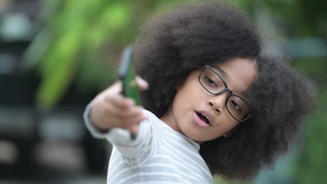 young cute african girl with afro hair showing phone in the streets outdoors