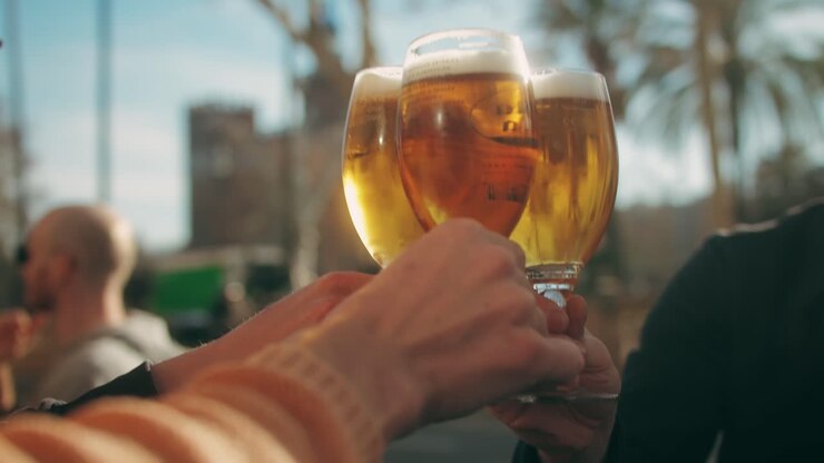 Young men having fun together,celebrating and cheers drinking beer and clinking glasses outdoorclose-up.