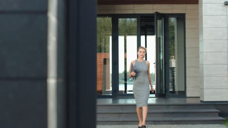 business woman going out building with laptop. blonde woman leaving office