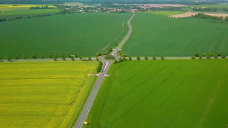 Vista-Aérea-De-Los-Campos-De-Cultivo-Con-Tráfico-Rodado-Y-Por-Carretera-Sinuoso-A-Través-De-él