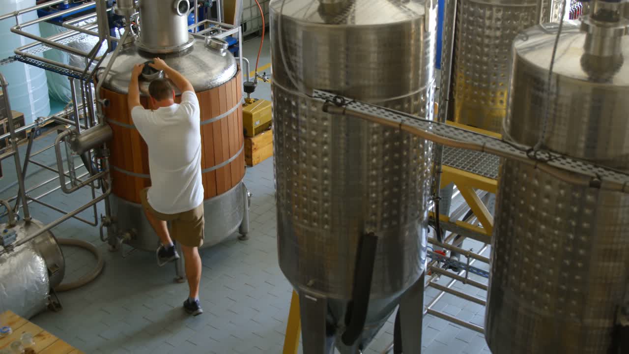 Male worker examining a distillation tank 4k