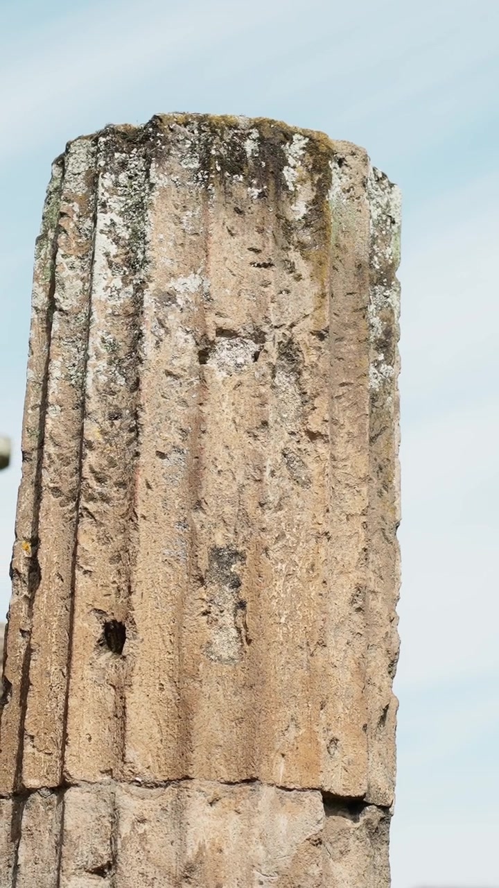 Primer plano de un fragmento de columna de piedra erosionada de Pompeya, mostrando bordes astillados, tallado desgastado y poca profundidad de campo en las ruinas antiguas.
