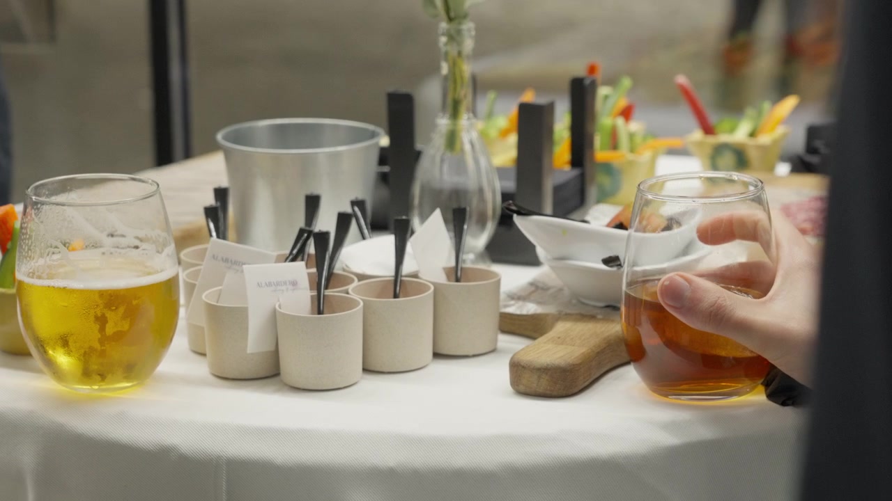 Ospiti che gustano bevande alcoliche e finger food da un tavolo da catering a un moderno evento aziendale o sociale.