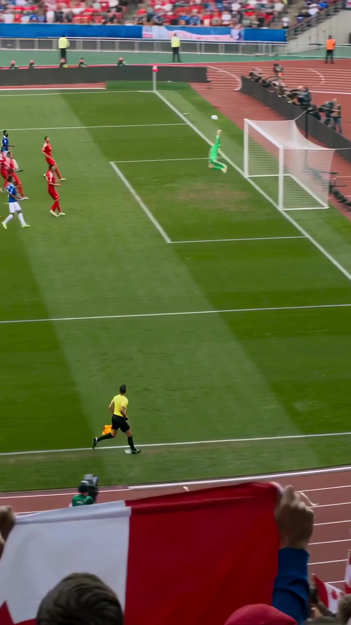 Video vertical: Jugador de azul con equipación azul lanzando un tiro libre a la portería, bandera canadiense, intentando marcar un gol.