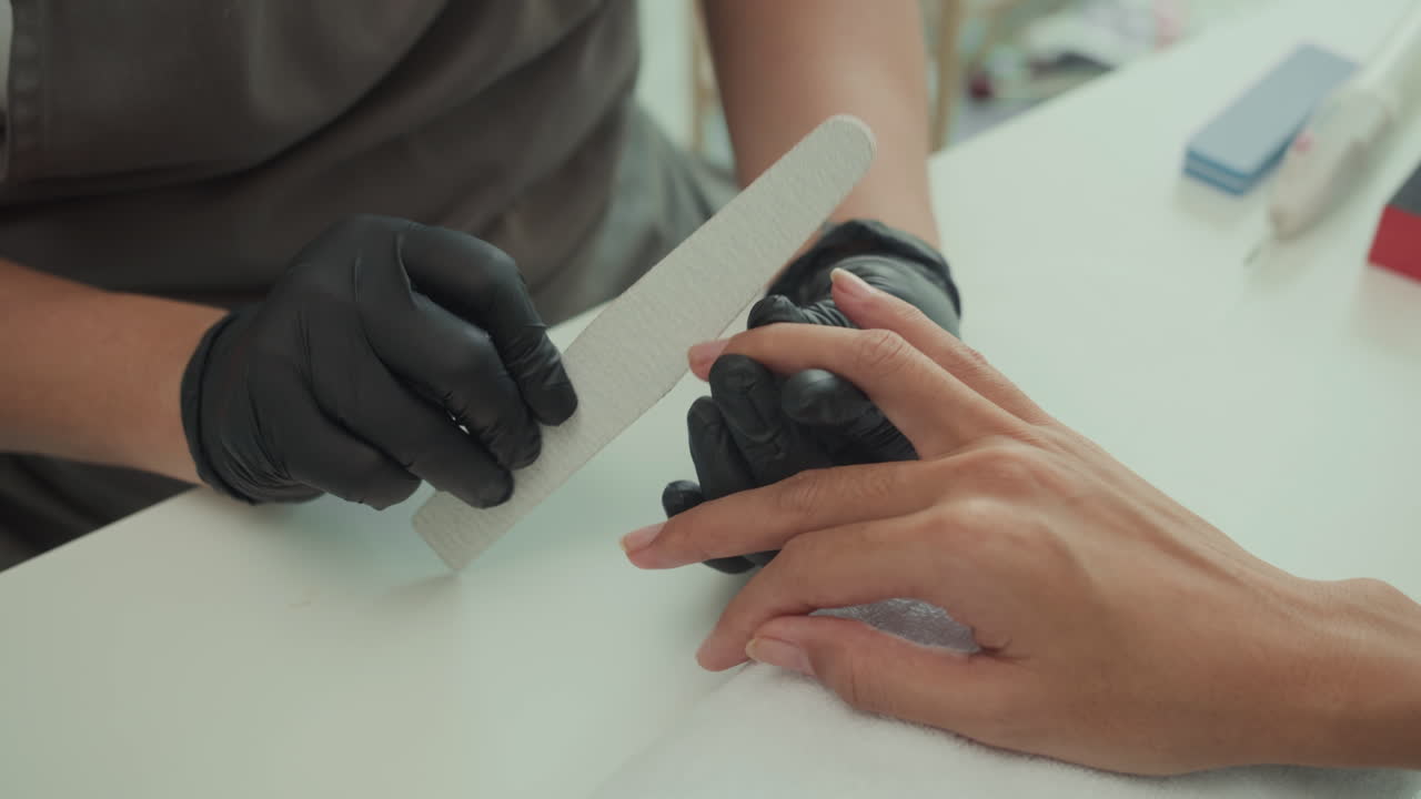Specialist Using File to Shape Nails of Client at Studio