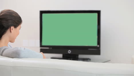 una mujer joven viendo la televisión.