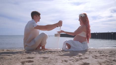 love couple pouring sand from hands on beach. happy couple having fun on beach