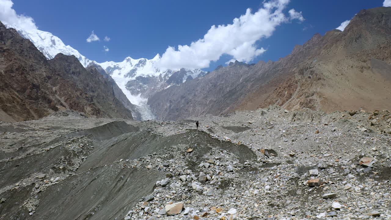 amplia toma de drones de una persona caminando en passu cones pakistán, toma aérea giratoria cinematográfica