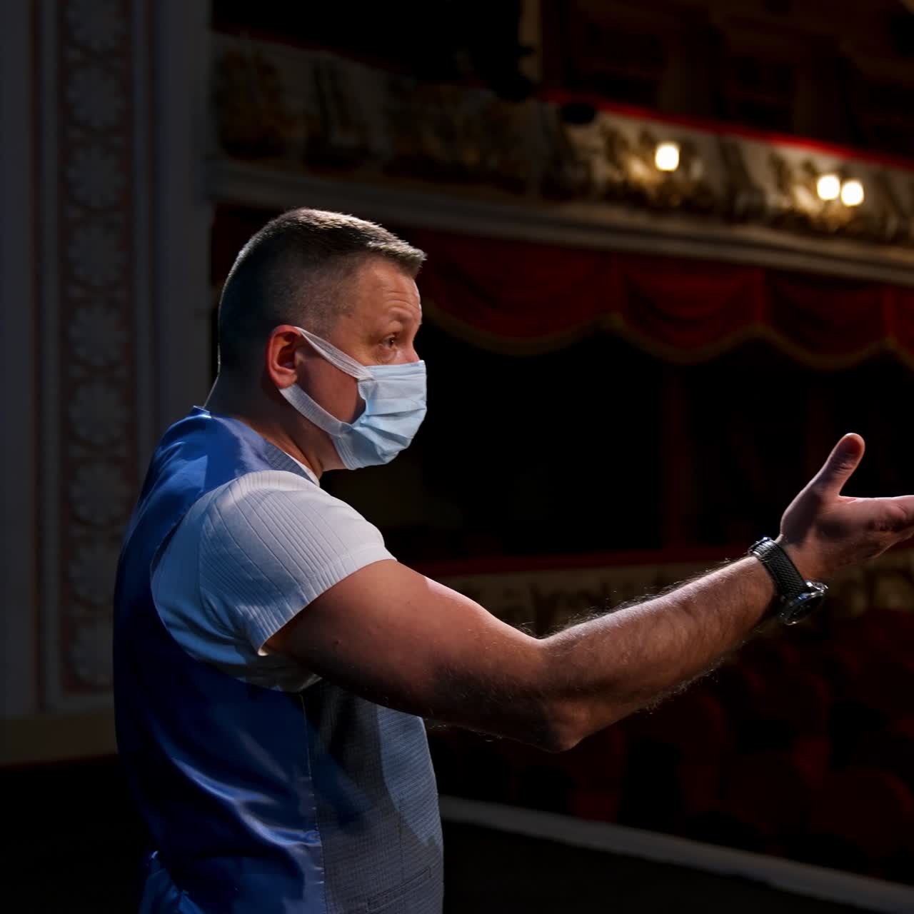 Actor on stage. Man in medical mask is talking to empty auditorium. Speaker in protective mask during the rehearsal. Rear view