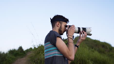 Young-man-taking-handheld-photos-in-a-landscape-environment