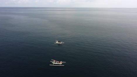 two fisherman boat isolated in middle of blue ocean in a tropical paradise during a sunny day , aerial minimalist landscape footage drone