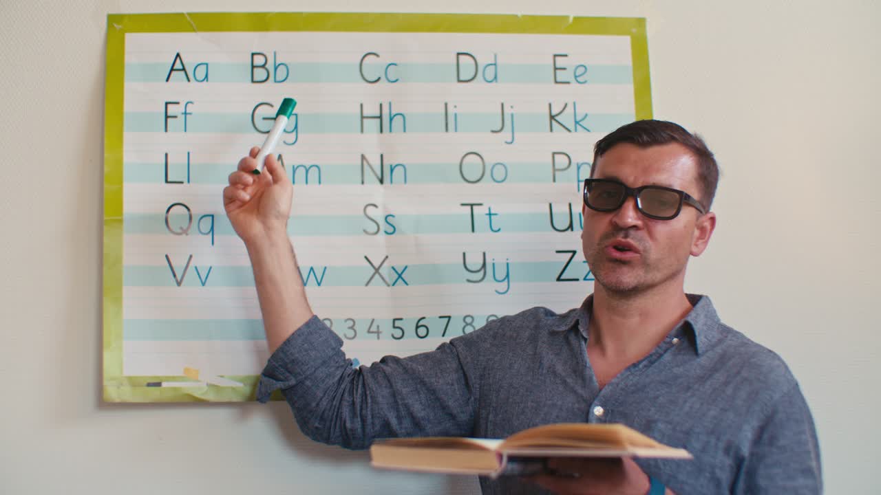 European Caucasian white male man English teacher tutor in glasses teaches English alphabet