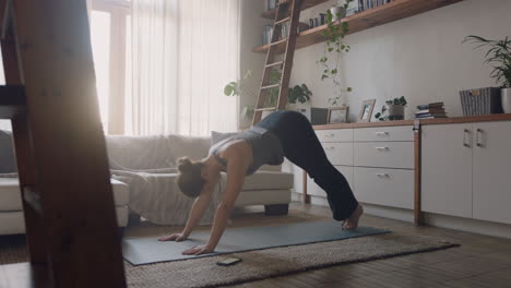 healthy yoga woman exercising at home practicing downward-facing dog pose in living room enjoying morning fitness workout