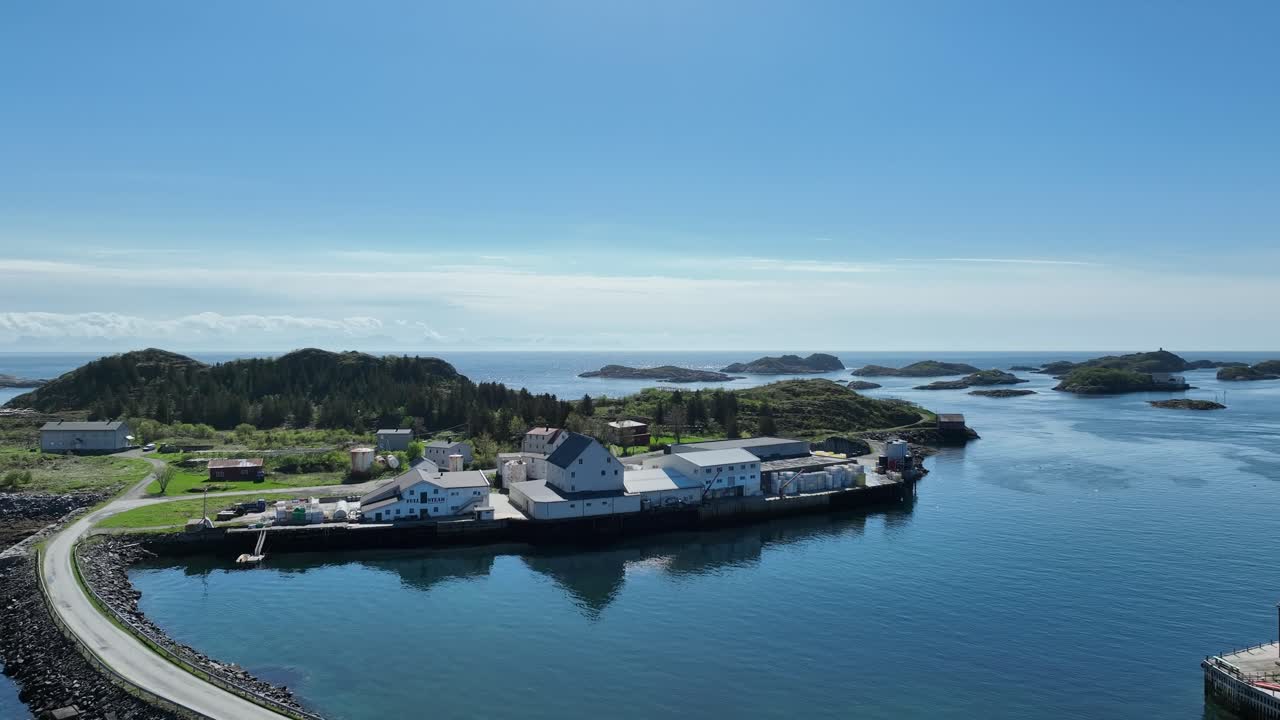 Aerial view over road and pier leading to Sauoya and Berleby in Henningsvaer with fish buildings and sea
